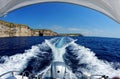 Fisheye view of boat stern trail on sea water and the cliffs of Gozo island in Malta Royalty Free Stock Photo