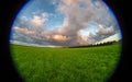 Fisheye view of a thundery shower over green fields during sundown Royalty Free Stock Photo