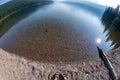 Fisheye wide angle view of Bowman Lake in Glacier National Park, with woman`s feet with sandals on the shoreline Royalty Free Stock Photo