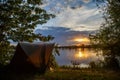 Fishing adventures, carp fishing. Angler, at sunset, is fishing with carpfishing technique. Camping on the shore of the lake.Carp