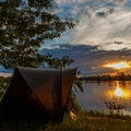 Fishing adventures, carp fishing. Angler, at sunset, is fishing with carpfishing technique. Camping on the shore of the lake.Carp