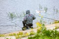 Fishing as a hobby. A man fishing with a fishing rod on the shore of a pond, river or lake, will spend his free time Royalty Free Stock Photo
