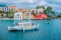 Fishing boat at anchor in blue sea bay of Assos village. Vivid colored houses with clouds in background, Kefalonia Royalty Free Stock Photo