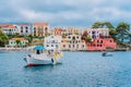 Fishing boat at anchor in blue sea bay of Assos village. Vivid colored houses with clouds in background, Kefalonia Royalty Free Stock Photo