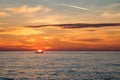 Fishing boat on the background of incredible golden sunrise, clouds and rising sun.