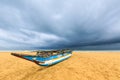 Fishing boat on the beach with dark clouds above the ocean Royalty Free Stock Photo