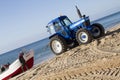 Fishing boat being towed on the beach by a tractor