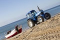 Fishing boat being towed on the beach by a tractor