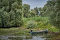 Fishing boat on a Danube Delta canal with lush green vegetation