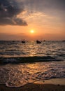 Fishing boat floating on tropical sea beach at sunset Royalty Free Stock Photo