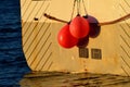 Fishing boat in harbor with red buoys hanging from the back