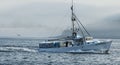 Fishing boat loaded with lobster traps heading out to sea passing porcupine Island  covered in fog Royalty Free Stock Photo