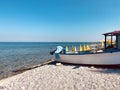 Fishing boat longboat on sandy pebbles on the beach with yellow umbrellas blue sky  sea water mediterranean sea Greece Royalty Free Stock Photo