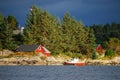 A fishing boat moored at a rocky shore. A view of the Norwegian fjord, a village with traditional red wooden houses and a dark Royalty Free Stock Photo