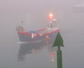 Fishing boat passing the starboard channel marker in the dawn fog in Mevagissey harbour south Cornwall England Royalty Free Stock Photo