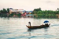 Fishing boat in river in Cambodia with village houses in the background. Mekong near Phnom Penh. Silhouette of fisherman.