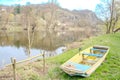 A fishing boat on the river shore surrounded by trees whiteout leaves spring day Royalty Free Stock Photo