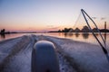 A fishing boat rushes along the river at dawn. View from the boat from the rear, net for fish.