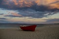 Fishing boat on sand beach after sunset. Boat at sea coast on cloudy evening sky. Summer vacation on sea. Fishing and