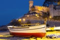 Fishing boat on a sandy beach in the evening against the background of the fortress. Royalty Free Stock Photo