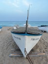Fishing boat on sandy beach at sunset in Pineda de Mar, Spain