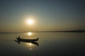 Fishing boat silhouette opposite sun on Taung Tha Man Lake at sunset. Amarapura, Mandalay, Myanmar