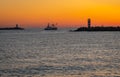 Fishing boat in silhouette shortly after sunset in between two lighthouses of south and north pier Ijmuiden, The Netherlands Royalty Free Stock Photo