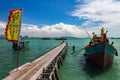 Fishing boat by a wooden bridge and a chinese flag in Tan Jetty, part of the Clan Jetties, Georgetown, Penang, Malaysia Royalty Free Stock Photo