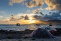 Fishing boats at anchor on the rugged mountainous coast of Sardinia at sunset with fishing nets in the foreground