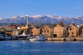 Fishing boats anchored by piers of Old Venetian shipyards or Neoria. Church bell tower and minaret, distant Cretan