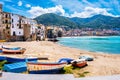 Fishing boats on beach of Cefalu, medieval town on Sicily island, Italy. Seashore village with historic buildings, clear Royalty Free Stock Photo