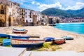 Fishing boats on beach of Cefalu, medieval town on Sicily island, Italy. Seashore village with historic buildings, clear Royalty Free Stock Photo