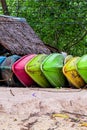 Fishing boats are bright green, pink and yellow lying on a sandy tropical beach against the backdrop of a hut and forest Royalty Free Stock Photo