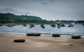 fishing boats floating in the ocean by a small hill on the beach Royalty Free Stock Photo