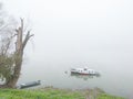 Foggy and gloomy autumn scene of boats moored along riverbank. Royalty Free Stock Photo