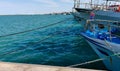 Fishing boats in the port at the dock, reflections of the sun in the green sea and taut hawsers Royalty Free Stock Photo