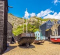 Fishing boats pulled onto the shingle rest between net drying sheds on the beach at Hastings, Sussex, UK Royalty Free Stock Photo