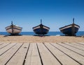 Fishing boats on a sandy beach near a wooden deck. Three boats on the Mediterranean coast on a sunny day Royalty Free Stock Photo