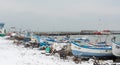 Fishing boats and a sunken pleasure boat on the snow-covered pier of Pomorie in Bulgaria