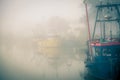 Fishing boats moored on a misty river.