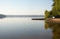 Fishing bridge on the shore of a forest lake in the early morning in the fog Royalty Free Stock Photo