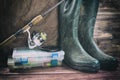 Fishing concept. Fishing tackles in boxes, rod, reel, fishing cage with rubber boots on timber board background. Toned image Royalty Free Stock Photo