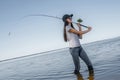 Fishing concept. Young fisherwoman makes a cast on background of skewed horizon line Royalty Free Stock Photo