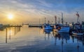 Fishing cutters and fishing boats stowed at the pier, lit by evening sun.Sunset over small harbor with fishing boats, cargo ship a Royalty Free Stock Photo