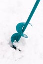 Ice fishing auger, lying on snow, used to drill holes in ice for winter fishing