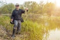 Fishing. Happy fisherman holding pike fish trophy and fishing rod at river Royalty Free Stock Photo