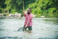 Fishing hobby and summer weekend. Bearded men fisher with fishing rod and net. Catching trout fish in net.