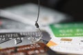Fishing hook is hooked on plastic bank credit card closeup