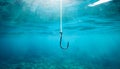 Fishing hook on string underwater. Clear sea or ocean water background Royalty Free Stock Photo