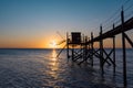 A fishing hut called carrelet with craft lifting net at sunset. Esnandes, charente maritime, France. The sun is caught in the net